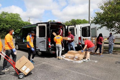 Individuals load boxes in the back of a van.