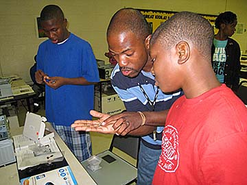 Cornelius Hamilton assists TechBridge Summer camp participant in identifying parts for the computer building project.