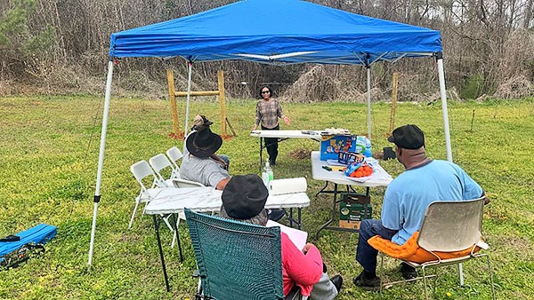 Gladys Hlorgbe presents to a group of people outside.