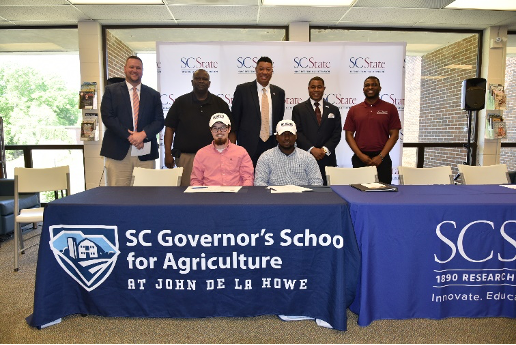 Jake Simpson, Jaquez Perry and supporters pose for picture at the Ag Innovation Scholarship signing ceremony.