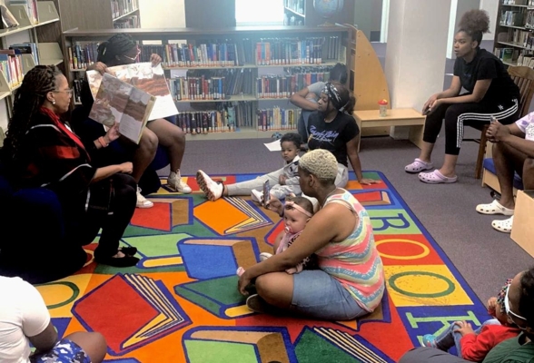 Extension staff reads to youth in the library.