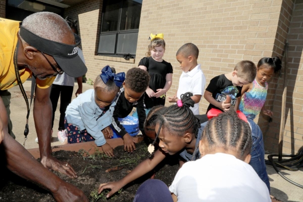 Roy Mosby, UAPB facility safety supervisor, talks to Child Development Center children about cleaning their garden after harvesting sweet potatoes.