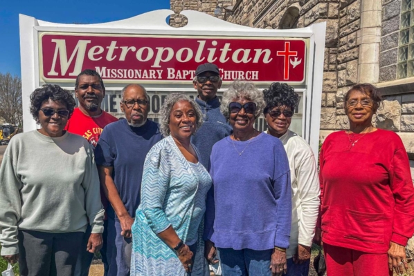 Members of the Metropolitan Missionary Baptist Church, Harvester's Food Bank volunteers and Lincoln University Regional Coordinator Marion Halim pose in front of the church's sign.