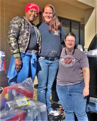 Terralon Chaney, Fort Valley State University’s Family and Consumer Sciences Extension agent, stands next to Salvation Army volunteers with bags of toys around them.