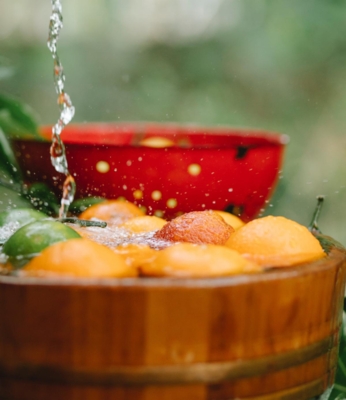 Water falls over fruit in a wooden basket. Photo by Any Lane from Pexels.