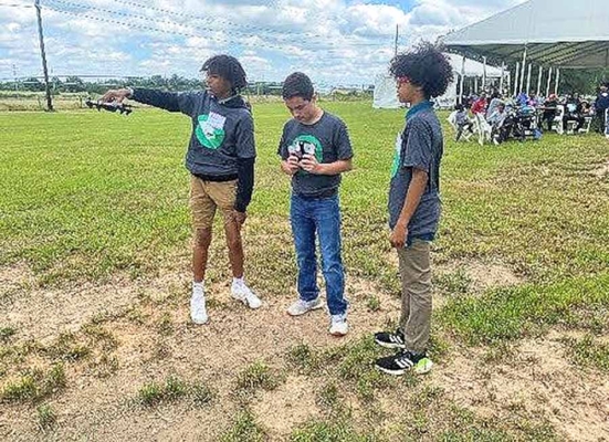 Three students operate a drone.