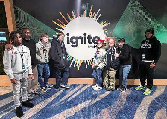 Group stands in front of ignite sign.