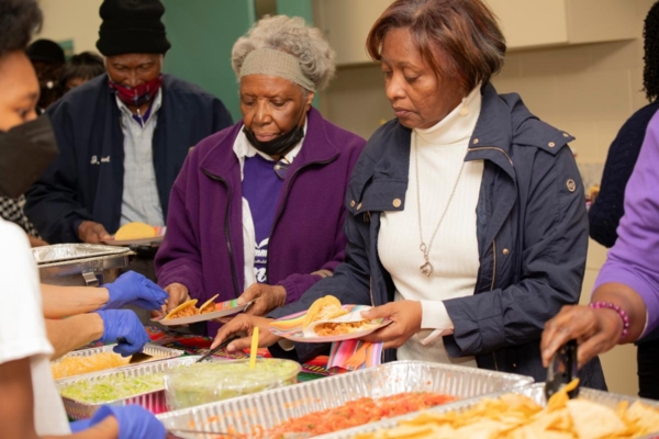 Individuals select food for their plates.