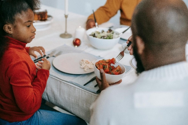 Family gather at table to eat a healthy meal.